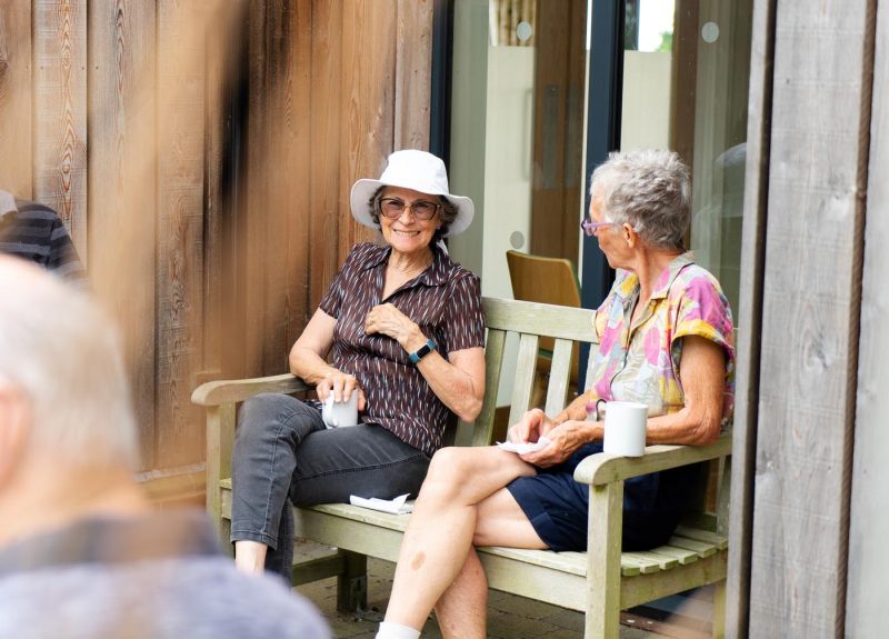 Elderly Women sitting on a bench drink tea